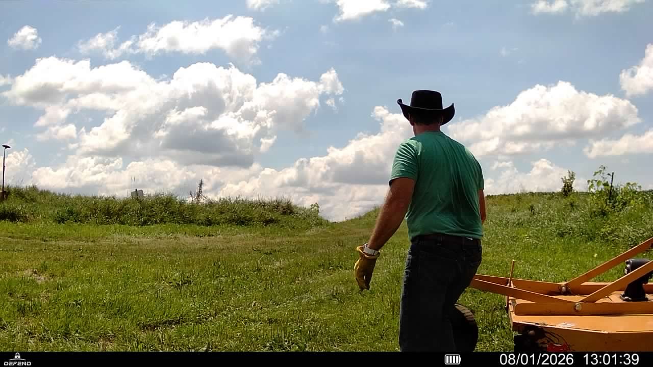 A trail camera view of a person out in the field